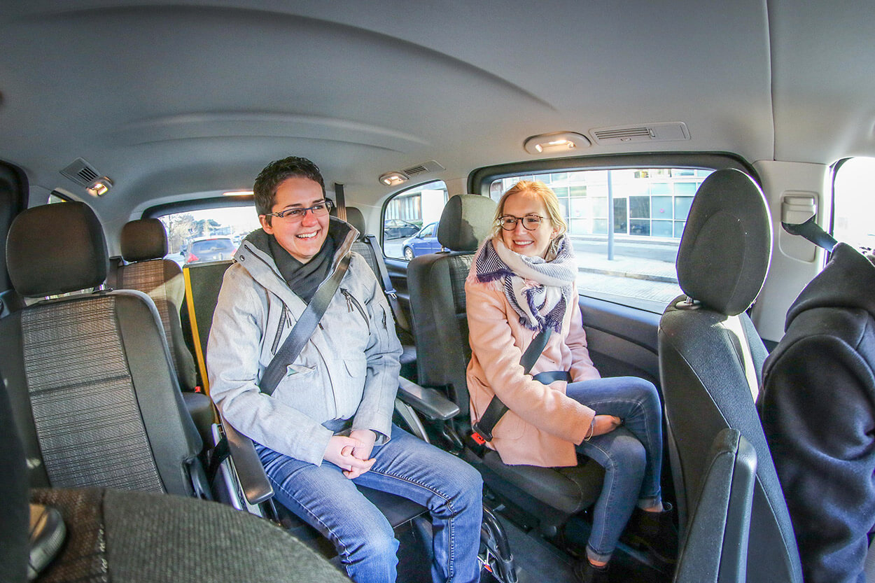 Le passager en fauteuil roulant installé au cœur de la voiture profite d&#039;une vue dégagée pour un trajet agréable et convivial grâce à la proximité avec les autres occupants.